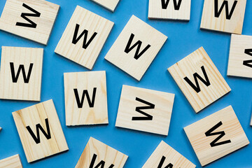 Alphabet W on wooden block lay flat on blue background. 5Ws concept