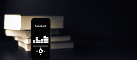 Audiobooks concept. Smartphone screen with audiobook application on paper books black background....
