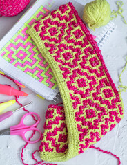 Eco friendly modern knitting with bright ethnic pattern. Pink yellow crochet fabric. We knit at home concept.