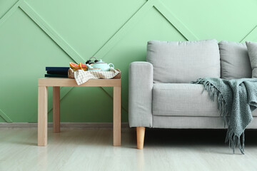 Stylish sofa and table near green wall