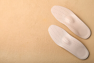 Pair of leather orthopedic insoles on color background