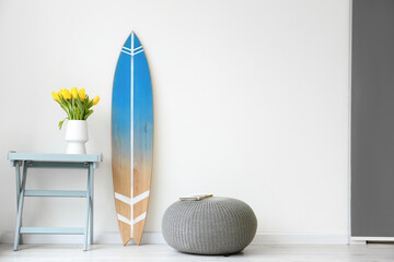 Surfboard, table and pouf near wall