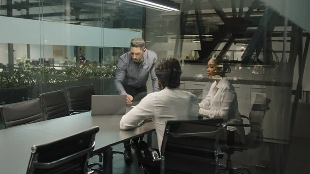 Indian arab male boss leader man coach corporate presentation for diverse businesspeople in office businessman presents new business plan project online software app with laptop speaking to interns