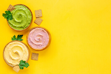 Fototapeta na wymiar Green and purple hummus with spinach and beets in bowls, top view