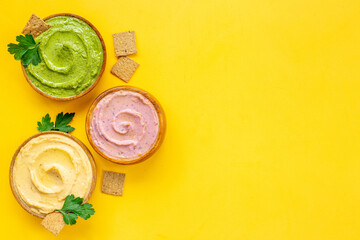 Green and purple hummus with spinach and beets in bowls, top view