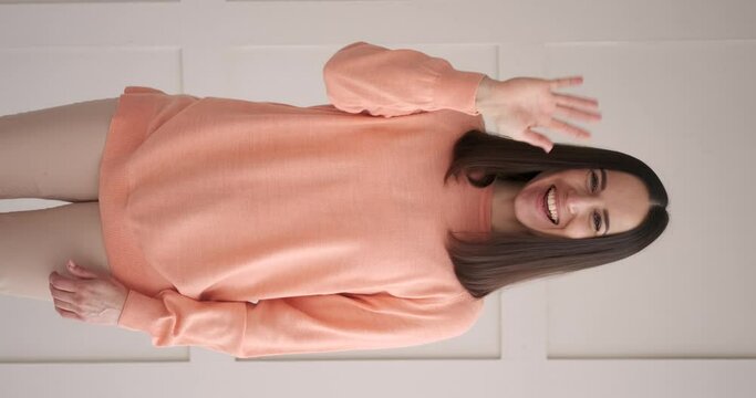 Vertical video of happy woman greeting by waving hand
