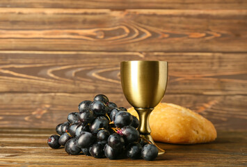 Cup of wine with grapes and bread on wooden background