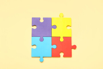 Colorful puzzle pieces on beige background. Concept of autistic disorder