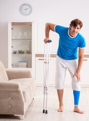 The leg injured young man with crutches at home