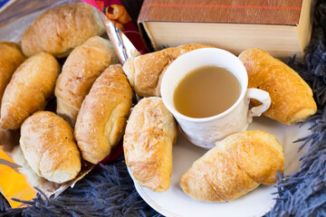 A cup of coffee and delicious croissants on a fluffy blanket