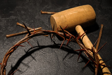 Crown of thorns with mallet and nails on dark background