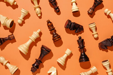 Scattered wooden chess pieces on an orange background