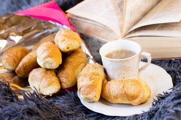 A cup of coffee and delicious croissants on a fluffy blanket, breakfast in bed