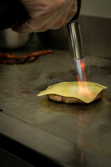 Vertical shot of a chef melting cheese with a flame torch