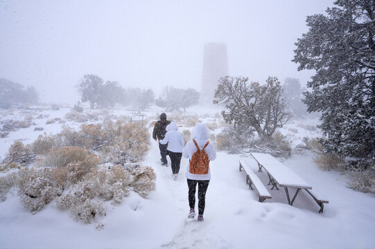 Family Hiking In Snow Storm On Winter Vacation. People Walking To The Desert View Watchtower. Grand Canyon National Park, Arizona, USA. 