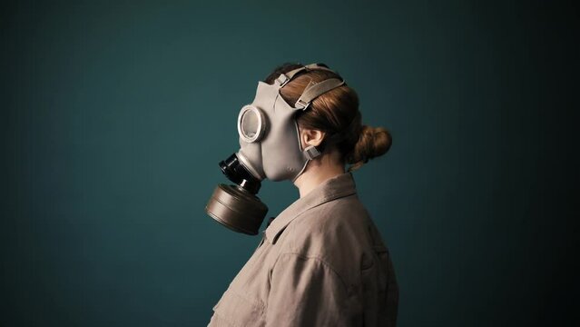 Pouse military in a gas mask, apocalypse, nuclear weapons, atomic explosion of a station, chemical and nuclear weapons protection. Girl in a mask on a green background, war