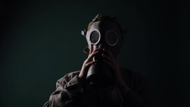 Pouse military in a gas mask, apocalypse, nuclear weapons, atomic explosion of a station, chemical and nuclear weapons protection. Girl in a mask on a green background, war