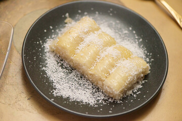 Closeup shot of the Middle Eastern baklava with coconut flakes on the black plate