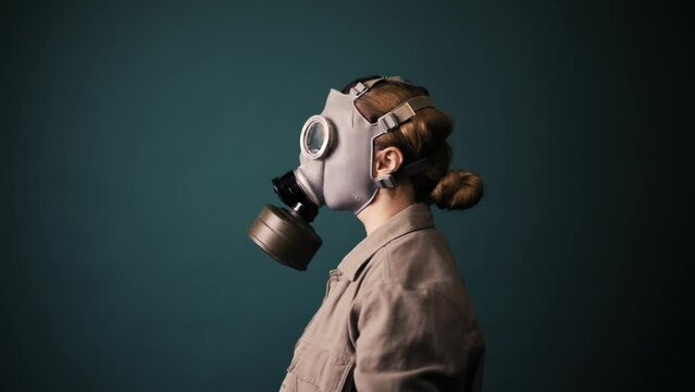 Pouse military in a gas mask, apocalypse, nuclear weapons, atomic explosion of a station, chemical and nuclear weapons protection. Girl in a mask on a green background, war