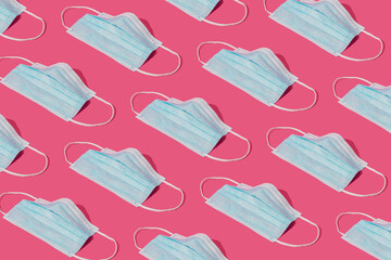 Pattern made with Coronavirus prevention medical surgical masks for corona virus protection. Global pandemic concept background. Trendy pink background.