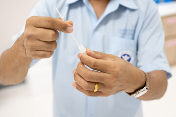 Medical technician hand taking a swab for corona virus sample from potentially infected.Man using rapid antigen test kit for self test at home.Antigen test kit for self collect nose swab