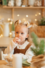 happy beautiful little girl eats gingerbread at the kitchen table. 