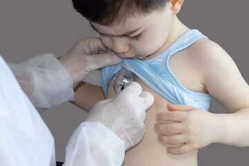 doctor or nurse, pediatrician, is examining a little boy with stethoscope. medical concept. health care and healthy lungs. respiratory infections prevention. grey background. 