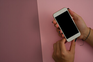 Top view flat lay of hand holding a smartphone with the white blank screen on a pinky purple background , for communication and technology concept.
