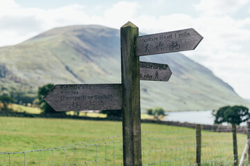 Wooden sign with near Wast Water or Wastwater lake located in Wasdale, a valley in the western part of the Lake District National Park, England, UK, beautiful summer day and blue cloudy sky