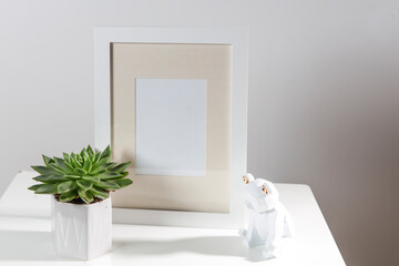 Fototapeta na wymiar Echeveria in a geometric pot next to a photo frame and a wooden bear figurine. Layout. Place for text. Scandinavian style