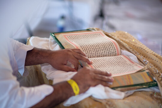 Closeup of a man reading the holy Granth Sahib at a traditional Indian wedding