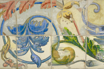 Vintage faded tiles with floral ornate. Damaged, weathered tiled wall. Heritage concept of traditional Spanish art
