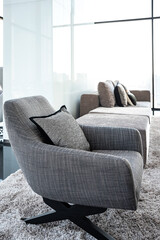 Black and white armchairs in the living room on the 29th-floor luxury apartment. There is a bare glass wall overlooking the city.