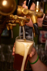 Obraz premium Hand bartender pouring large lager beer. Light cold filtered beer in glass beaker.