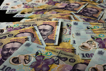 Closeup shot of 100 leu banknotes spread out on the black surface