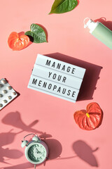 Text Manage your menopause. Pink frame in hand. Menopause, hormone therapy concept. Estrogen...