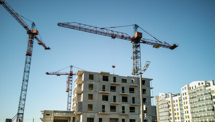Fototapeta premium Tower cranes at the construction site. Construction of panel high-rise buildings.
