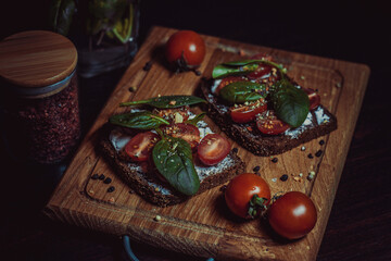 Fototapeta na wymiar Sandwich with cream cheese, cherry tomatoes, spinach and spices on a wooden board. Home and restaurant cuisine. Delicious healthy veggie food. High quality photo