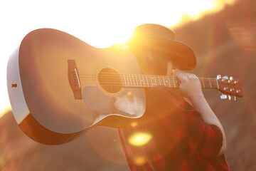cowgirl with guitar at sunset