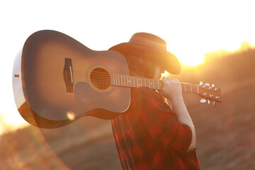 cowgirl with guitar at sunset