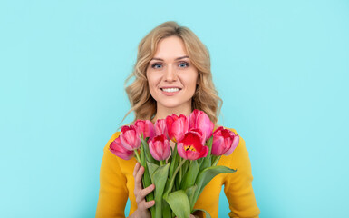 face of happy young woman with spring tulip flowers on blue background