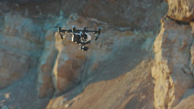 In rock mountains drone flies. Modern technologies for shooting photos and videos from above. Golden hour