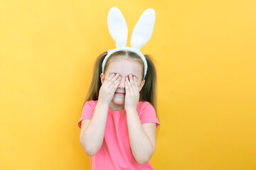 cheerful girl with rabbit ears on her head on a yellow background. Funny crazy happy child. Easter...