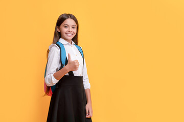 happy teen girl in school uniform carry backpack showing thumb up, copy space, september 1