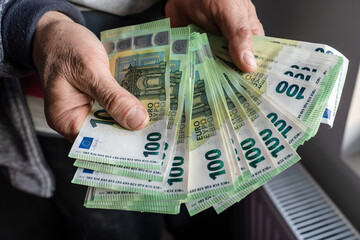 Close up on hands of unknown caucasian senior man holding and counting 100 euro banknotes money...