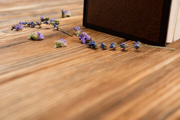 Naklejka premium book and dried lavender flowers on blurred wooden surface.