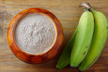 Organic green banana flour, crushed, raw and dry in wooden bowl. gluten free flour