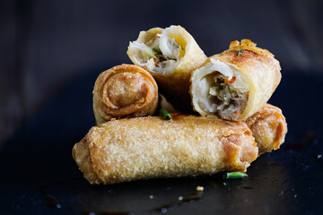 Fresh stack of egg rolls. Top eggroll is broken open to see the ingredients inside. Selective focus with blurred foreground and background. 