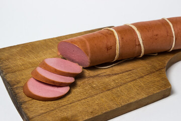 Boiled sausage on a white background. Sliced sausage stick on a wooden board. Sausage product.