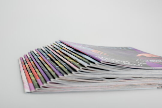stack of blurred magazines on grey background.